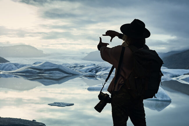 Female photographer at glacier lagoon. Sunset