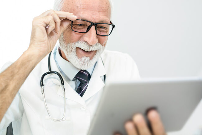 Happy senior male doctor looking at a digital tablet.