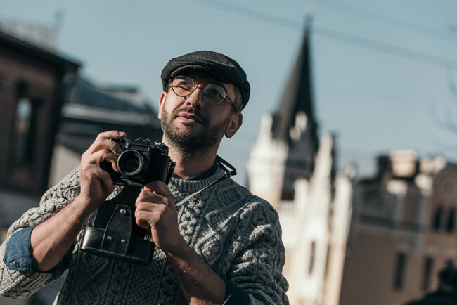handsome adult man with vintage film camera in old european town