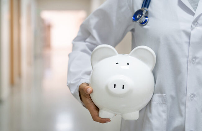 Doctor holding a piggybank at the hospital – medical insurance