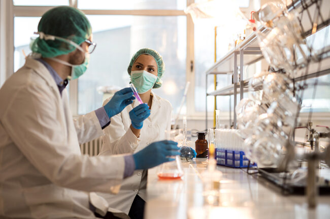 Two forensic scientists cooperating while working on medical research in laboratory.