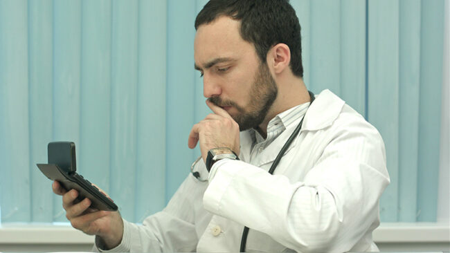 Serious male doctor focus on calculation of costs and revenues