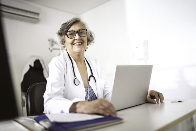 Portrait of senior female doctor using laptop at doctor’s office