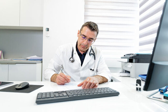 Doctor writing prescription at his desk