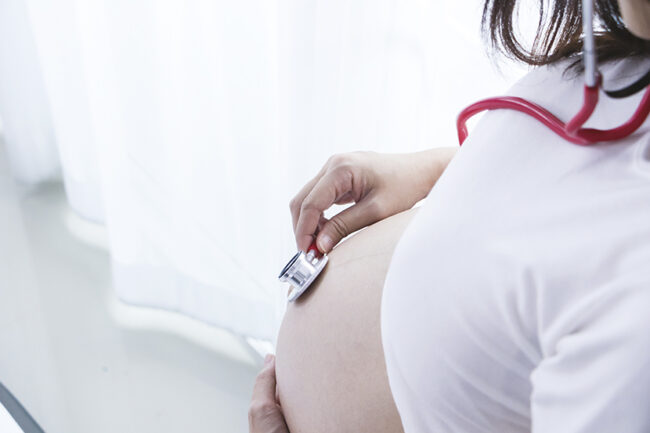 Portrait of Beautiful young pregnant women using stethoscope listening to her tummy.Pregnancy health care preparing for baby concept.Motherhood among teenage mother.