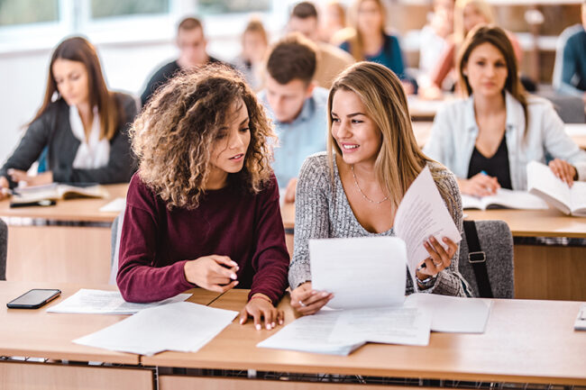 Young female students cooperating on a class in the classroom.